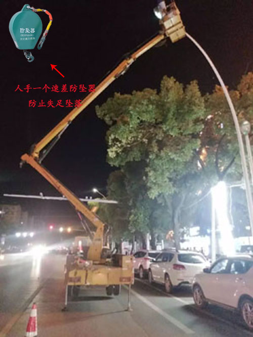 夜晚工人站在升降平臺車上進(jìn)行路燈更換